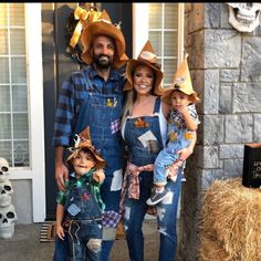 a man, woman and two children dressed up in scarecrow hats standing on the front porch