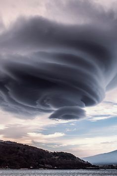 a very large cloud is in the sky over some water