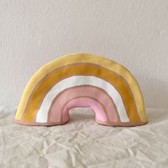 a pink, yellow and white rainbow shaped pillow sitting on top of a sheet of paper