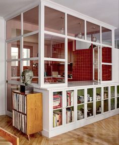 a living room filled with lots of furniture and bookshelves next to a red couch