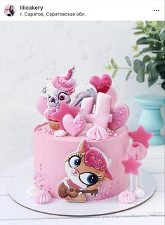 a pink birthday cake decorated with an image of a unicorn and cupcake on top