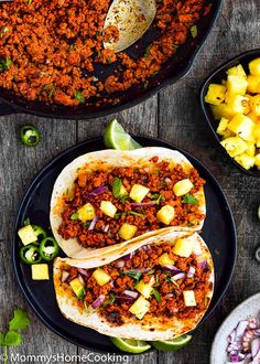 two tacos with pineapple salsa on the side next to some other food items