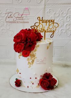 a white and gold birthday cake with red roses