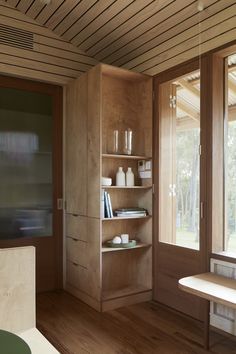 a room with wooden floors and shelves filled with books, vases and other items