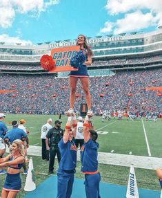 the cheerleaders are doing stunts on the field at an orange and blue football game