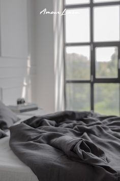 an unmade bed in front of a large window with the words amara on it