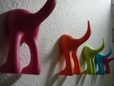 three different colored plastic dinosaurs are hanging on the wall next to each other in a row