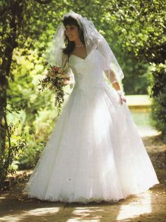 a woman in a wedding dress is walking through the woods