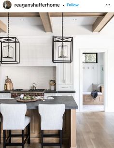 an image of a kitchen setting with white chairs and black counter tops on the island