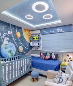 a child's bedroom decorated in blue and white with an outer space theme on the wall