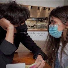 two people sitting at a table wearing face masks