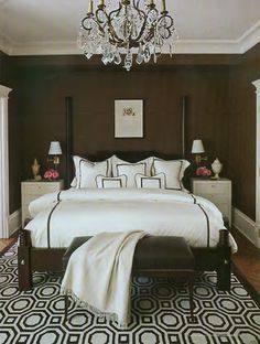 a bedroom with brown walls and white bedding, chandelier above the bed