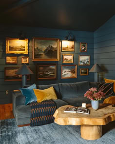 a living room with blue walls and pictures on the wall above the couch, along with a coffee table