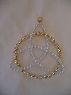 a white and gold beaded necklace hanging from a string on top of a table