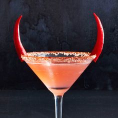 a red devilish cocktail garnished with gold flakes and an orange liquid