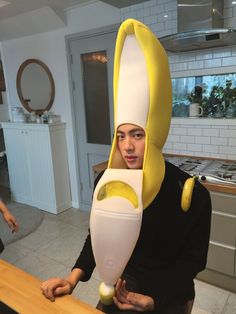 a man in a banana suit holding a banana peel mask on his head while standing next to a counter