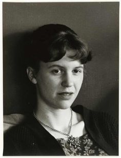 an old black and white photo of a woman with short hair wearing a beaded necklace