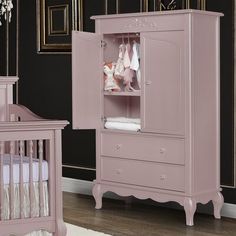 a baby crib and dresser in a room with black walls, white rugs and pink furniture