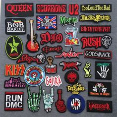 various patches and stickers are displayed on a gray surface with white writing that says queen sequins u2 must be