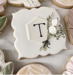 decorated cookies with the letter t and flowers on them are displayed for guests to eat