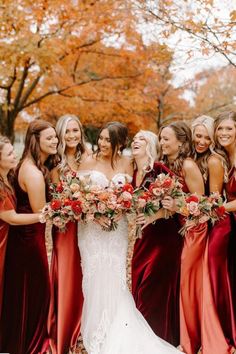 a group of women standing next to each other in front of trees with leaves on the ground