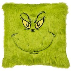 a green pillow with an angry grin face drawn on the front and side of it