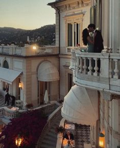 two people standing on the balcony of a building with candles lit in front of them