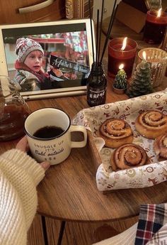 a person sitting at a table with coffee and cinnamon rolls in front of them on a tray