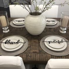 the table is set with white plates and place settings