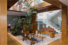 a living room filled with lots of furniture next to a stair case and potted plant