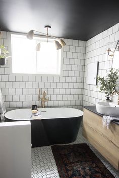 a black and white bathtub in a bathroom next to a rug on the floor