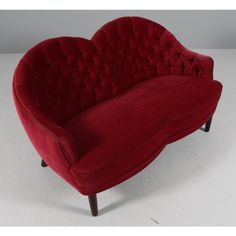 a red couch sitting on top of a white floor next to a chair with wooden legs