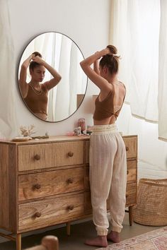 a woman standing in front of a mirror brushing her hair