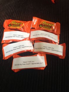 four packets of candy sitting on top of a black table next to an orange bag