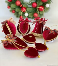 red velvet heart ornaments with bows and ribbons on white surface next to christmas wreaths