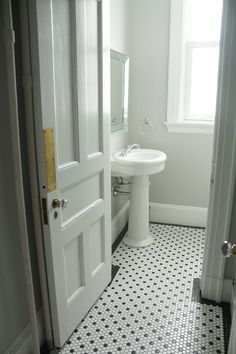 a white bathroom with black and white flooring next to a sink in the corner