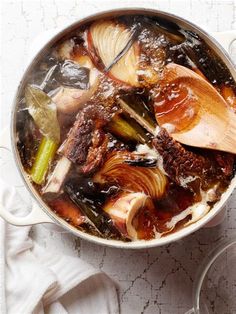 a pot filled with meat and vegetables sitting on top of a table next to a spoon