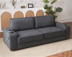 a gray couch sitting on top of a wooden floor next to a potted plant