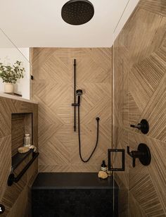 a bathroom with a shower head, black fixtures and wood paneling on the walls