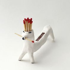 a white toy with red and gold sticks sticking out of it's head, in front of a white background