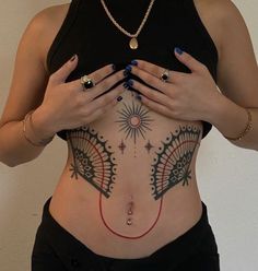 a woman with tattoos on her stomach is holding her hands in front of her chest