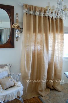 a living room with a chair, mirror and chandelier