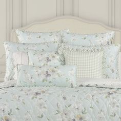 the comforter is made up with white and blue flowers on it, along with matching pillows