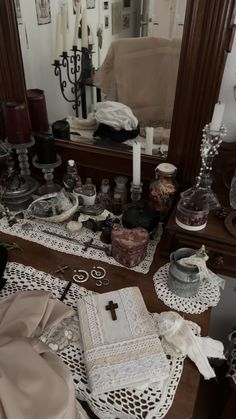 the table is covered with many items and has a cross on it in front of a mirror