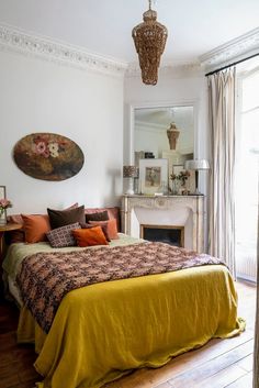 a bedroom with a large bed, fireplace and painting hanging on the wall above it