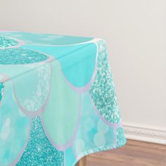 a blue table cloth with white and green designs on it, sitting in front of a wood floor