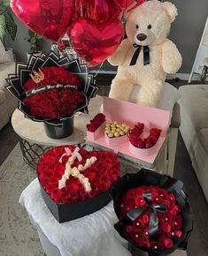 a teddy bear sitting on top of a table next to two heart shaped boxes filled with roses