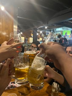 several people are toasting with beer at a bar