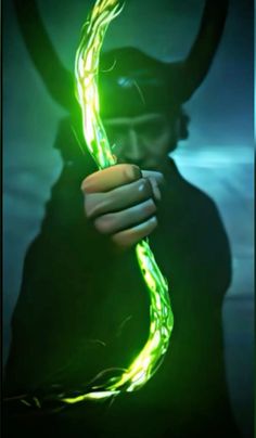 a man holding a glowing green object in his hand and wearing a hat with horns on it