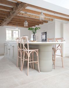 a kitchen with an island and chairs in the center, surrounded by wooden beams on the ceiling